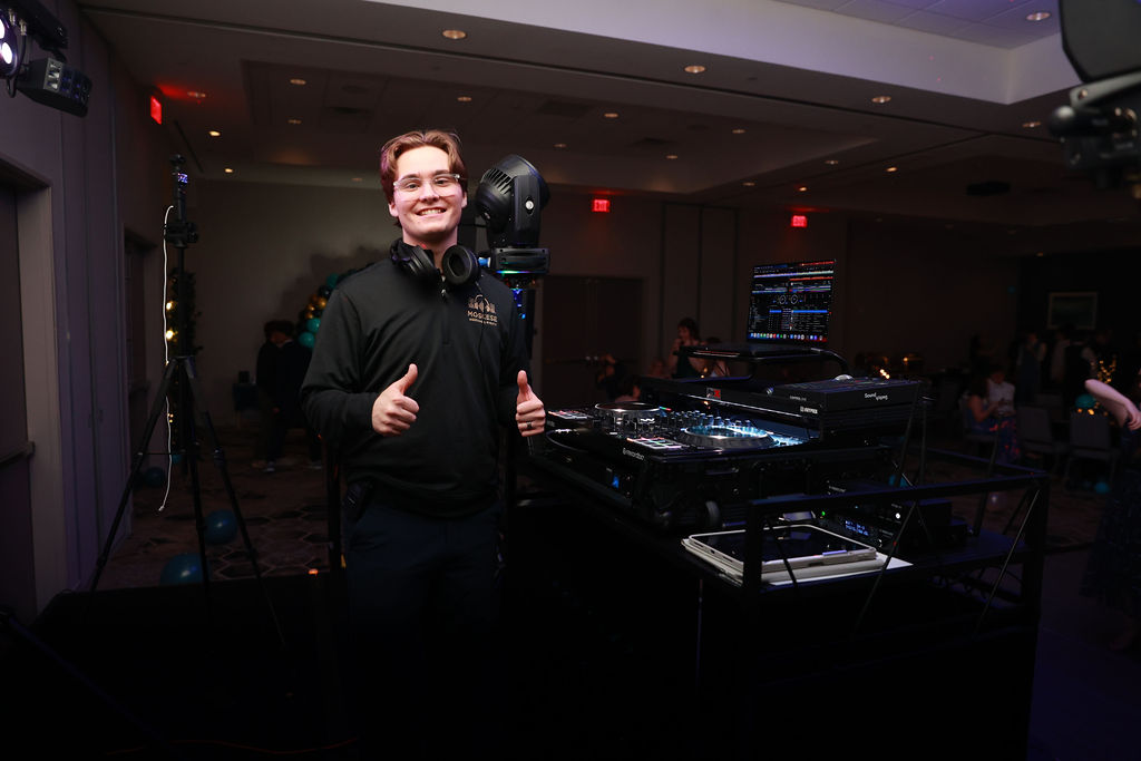 Javan smiling beside his professional DJ setup at a wedding